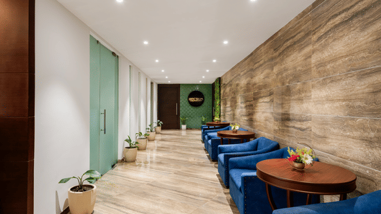 Tables and seaters placed against a patterned wall with planters opposite to them and the logo of Spectrum in the background at Voyage Milestone Hotel And Banquet 